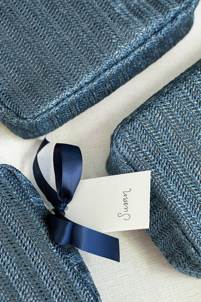 Three blue woven boxes are arranged on a light surface, one with a navy ribbon and a tag labeled Susan.