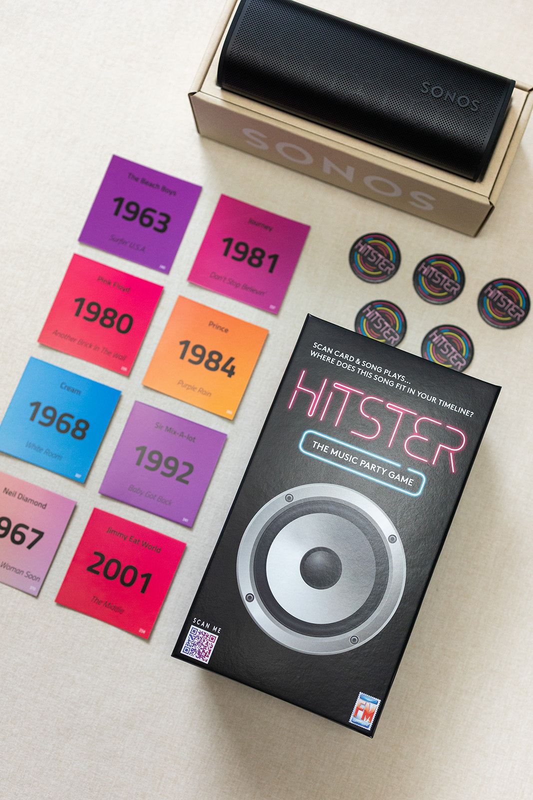 A LUX BOX co. Tune In & Play On set features a speaker in its box, a music game party box, colorful year cards from 1963-1981, and round tokens arranged on a light surface, all ready for a fun song battle.