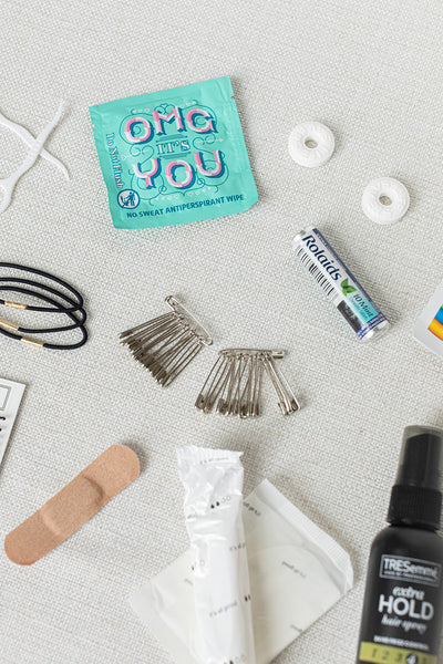 The chic LUX BOX Bathroom Amenities Tray - THE HERS includes bobby pins, hair ties, fashion tape, a bandage, antiseptic wipe, breath mints, dental flossers, and a small hairspray bottle on a light surface.