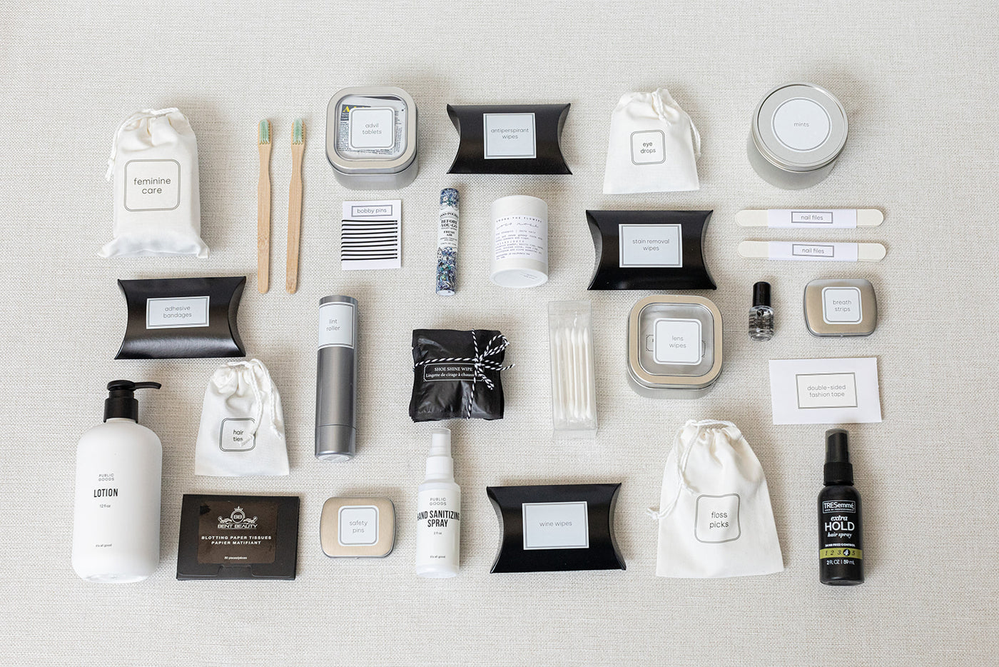 The Bathroom Amenities Tray- THE DELUXE by LUX BOX neatly displays personal care and grooming essentials, including bottles, jars, pouches, and toothbrushes on a light surface.