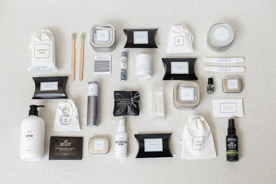 The Bathroom Amenities Tray- THE DELUXE by LUX BOX neatly displays personal care and grooming essentials, including bottles, jars, pouches, and toothbrushes on a light surface.